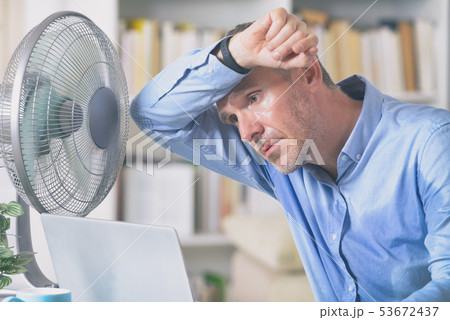 Man suffers from heat in the office or at home 53672437