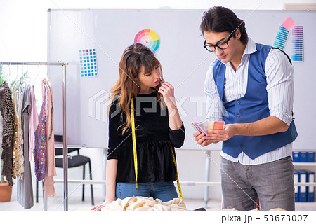 Young male tailor teaching female student  53673007