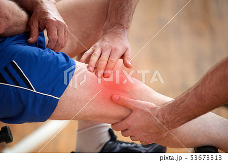 Male hands doing a massage to male knee at gym. 53673313