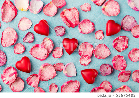Chocolate heart shaped candies with rose candied sugared petals. Blue background. Top view. 53675485