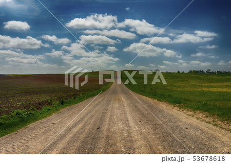 Gravel country road through farm fields and meadow Gravel country road through farm fields and meadow 53678618