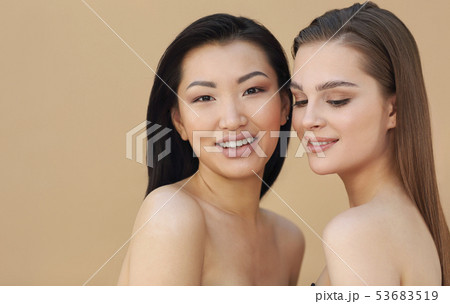 Two beautiful multicultural young women hugging Two beautiful multicultural young women hugging 53683519