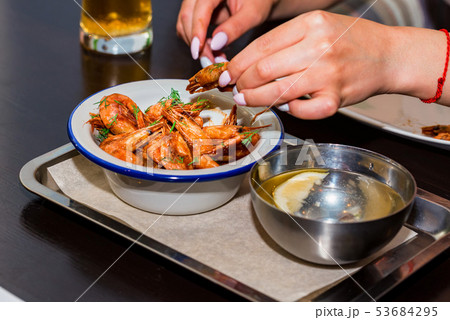 Close up hands of young woman eating shrimps in restaurant Close up hands of young woman eating shrimps in restaurant 53684295