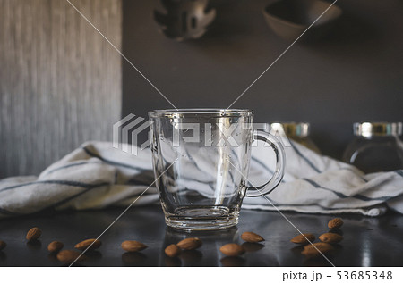 Glass empty mug. Around almonds, staged photo. 53685348