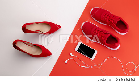 A studio shot of pair of running vs high heel shoes on color background. Flat lay. A studio shot of pair of running vs high heel shoes on color background. Flat lay. 53686263