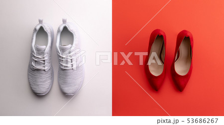 A studio shot of pair of running vs high heel shoes on color background. Flat lay. A studio shot of pair of running vs high heel shoes on color background. Flat lay. 53686267