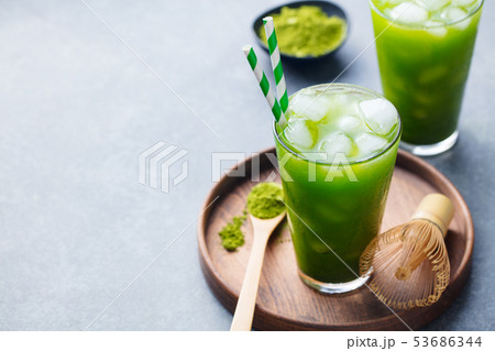 Matcha ice tea in tall glass on wooden plate. Grey stone background. Copy space. Matcha ice tea in tall glass on wooden plate. Grey stone background. Copy space. 53686344