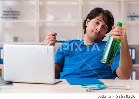 Young male doctor drinking in the office  53688226