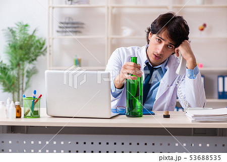 Young male doctor drinking in the office  53688535