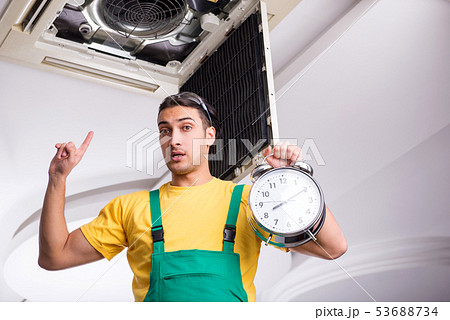 Young repairman repairing ceiling air conditioning unit  53688734