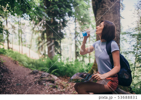 Woman resting drinking water while hiking in forest. Woman resting drinking water while hiking in forest. 53688831