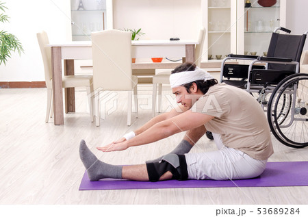 Injured young man doing exercises at home Injured young man doing exercises at home 53689284