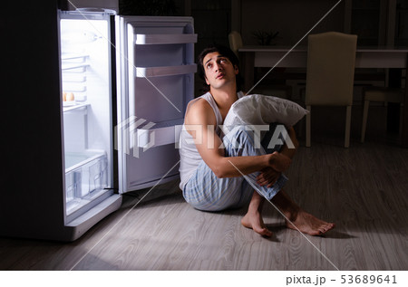 Man breaking diet at night near fridge Man breaking diet at night near fridge 53689641