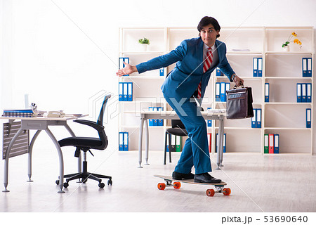 Young handsome businessman with longboard in the office Young handsome businessman with longboard in the office 53690640