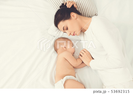 Young mom and her cute baby sleeping in bed Young mom and her cute baby sleeping in bed 53692315