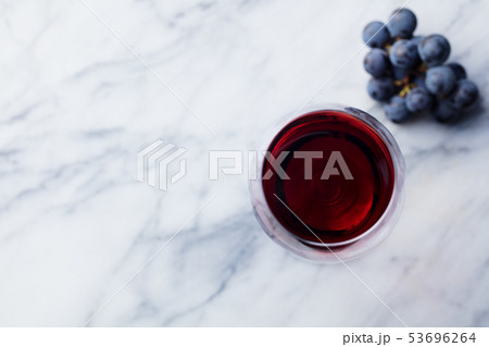Red wine in glass with fresh grape on marble table background. Top view. Copy space. 53696264