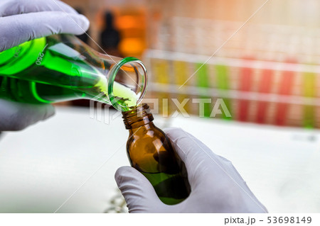 Researcher is pouring chemicals into bottles. 53698149