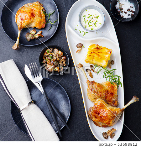 Duck legs confit with potato gratin and mushroom sauce. Top view. Slate background. 53698812