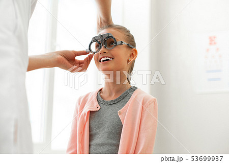 Beaming cute little kid calmly sitting in bright cabinet Beaming cute little kid calmly sitting in bright cabinet 53699937