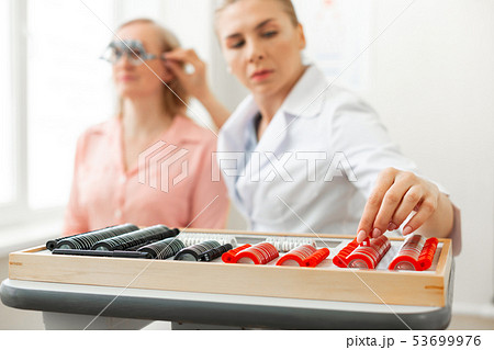 Serious doctor in white robe taking off needed lens Serious doctor in white robe taking off needed lens 53699976