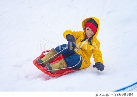 Little Japanese girl is sliding down the snow sled 53699984