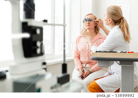 Gentle long-haired doctor correcting placement of glass device Gentle long-haired doctor correcting placement of glass device 53699992