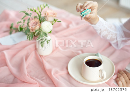 Young beautiful caucasian bride enjoying breakfast from french macaroon and coffee on a wooden table 53702576