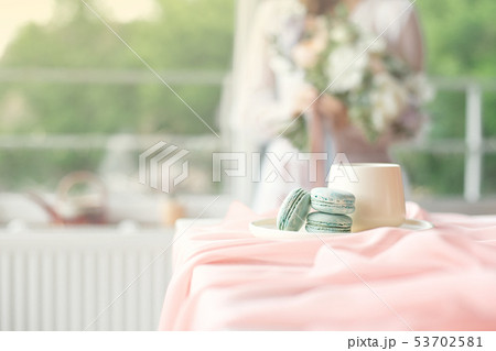 Young beautiful caucasian bride enjoying breakfast from french macaroon and coffee on a wooden table 53702581