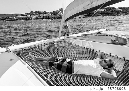 Sporty man relaxing on a luxury catamaran sailing boat. Sporty man relaxing on a luxury catamaran sailing boat. 53708098