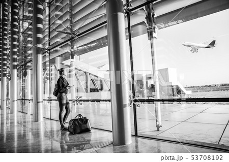 Young woman waiting at airport, looking through the gate window. 53708192