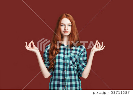 Trying to calm down. Smiling beautiful redhead girl meditating in studio. No stress concept 53711587