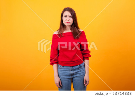 Portrait of beautiful young woman looking annoyed at the camera over yellow background 53714838