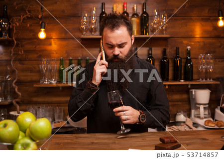 Bearded young batender talking on the phone taking care of his business. 53714857