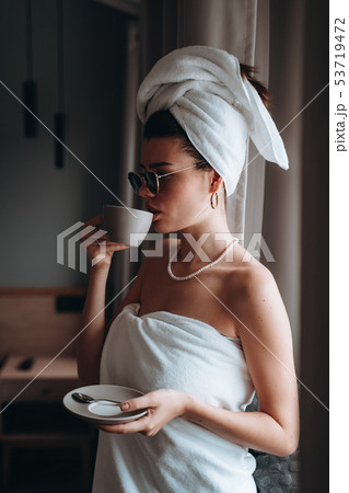 Girl wrapped in a towel after a shower drinking coffee Girl wrapped in a towel after a shower drinking coffee 53719472