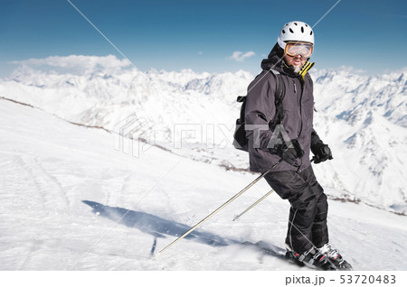 Bearded male skier in a helmet and a ski mask brakes with snow powder on skis against the background 53720483