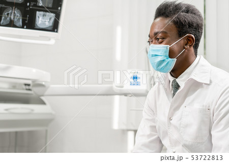 Young African male dentist shows x-rays on the monitor. Medicine, health, stomatology concept 53722813