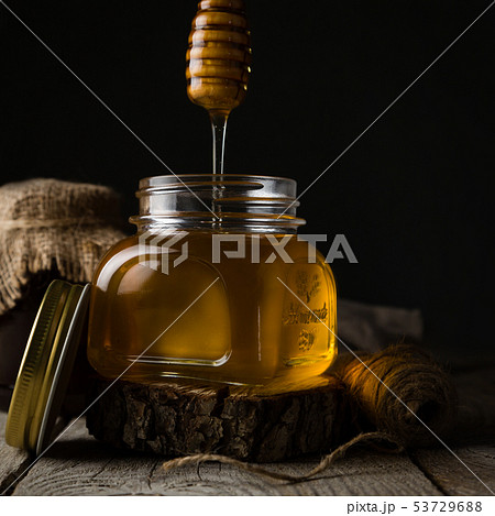 Golden honey in glass jar with dipper Golden honey in glass jar with dipper 53729688