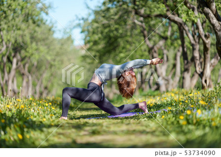 Photo of girl with arms raised practicing yoga in woods 53734090