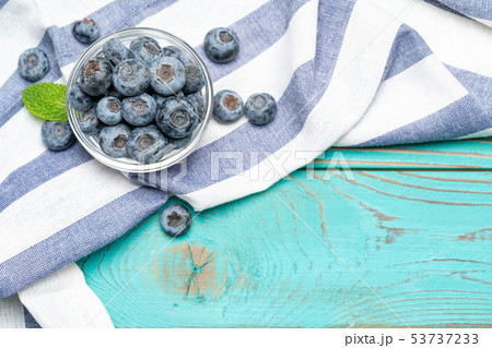 Glass bowl full of fresh blueberries with herbs on wooden background Glass bowl full of fresh blueberries with herbs on wooden background 53737233