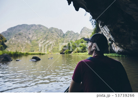 Man on boat floating through to cave 53739266