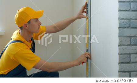 Repairman making measurement of wall. 53745797