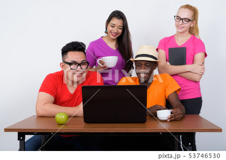 Happy diverse group of multi ethnic friends smiling and using la 53746530