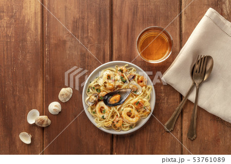 Seafood pasta. Tagliolini with mussels, shrimps, clams and squid rings, with a glass of white wine Seafood pasta. Tagliolini with mussels, shrimps, clams and squid rings, with a glass of white wine 53761089