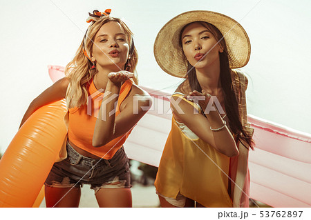 Face-portrait of ladies holding water toys and sending air kisses. 53762897