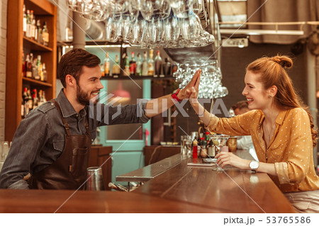 Radiant woman giving a high five to a bar worker 53765586