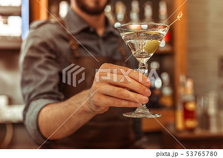 Close-up photo of bar worker holding a martini cocktail 53765780