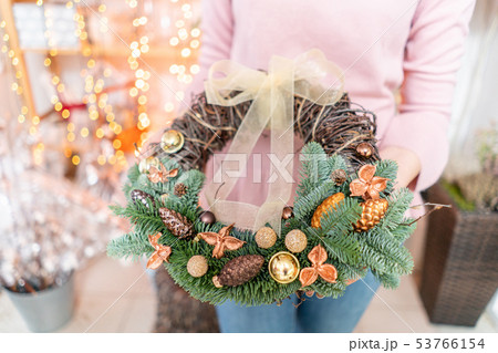Beautiful festive wreath of fresh spruce with ball toys in woman hands. Christmas mood. Bokeh of Beautiful festive wreath of fresh spruce with ball toys in woman hands. Christmas mood. Bokeh of 53766154