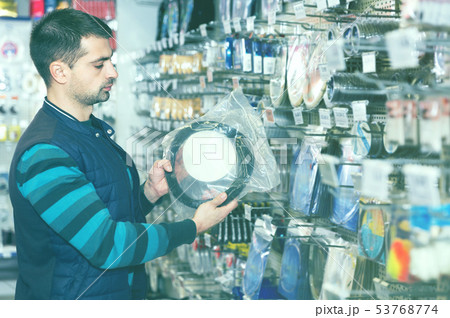 Young male choosing fishing variety accessories in the sports shop Young male choosing fishing variety accessories in the sports shop 53768774