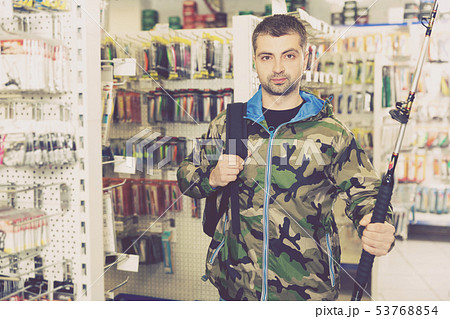 Fisherman in fishing clothing standing with fishing rod Fisherman in fishing clothing standing with fishing rod 53768854