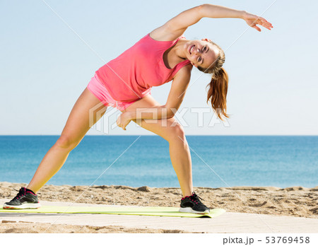 Woman exercising yoga at sea beach 53769458